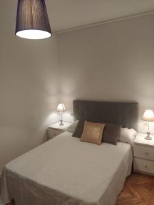 1 dormitorio con 1 cama blanca grande y 2 lámparas en Bonito piso en el centro de Ourense, en Ourense