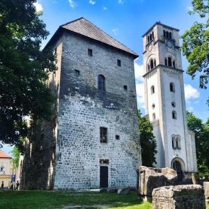 un antico edificio in pietra con torre dell'orologio di Swiss Plus Hotel a Bihać