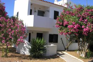 ein weißes Gebäude mit rosa Blumen davor in der Unterkunft Retur Algarve Beach House in Castro Marim