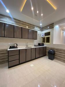 cocina grande con armarios marrones y fregadero en قمم بارك Qimam Park Hotel 2, en Abha