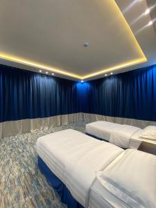 two beds in a room with blue curtains at قمم بارك Qimam Park Hotel 2 in Abha