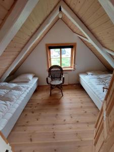 Pokój z 2 łóżkami i krzesłem na poddaszu w obiekcie Turf House Cottage - Near Airport w mieście Miðvágur