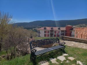 un banco sentado en una colina con una casa en el fondo en El Rinconcico en Valdelinares