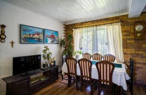 a dining room with a table with chairs and a television at Leśny Dworek in Darłowo