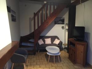 uma sala de estar com um sofá e uma escada em Maison au carrefour des terroirs 