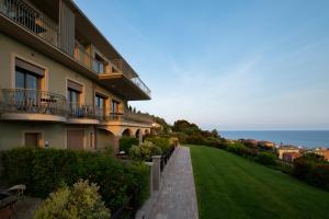 a building with a green lawn next to the ocean at Villa LeA in Imperia