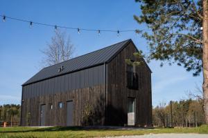 a wooden barn with a black roof at Domki Czarny Bocian in Białogóra