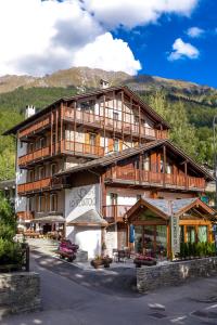 a large wooden building with mountains in the background at Hotel Lo Scoiattolo in Courmayeur