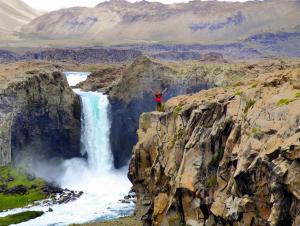 a man standing on a cliff next to a waterfall at Colbun in Colbún