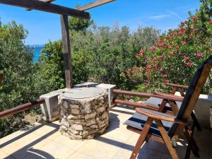 a patio with a wooden chair and a stone stump at Orkula Hidden Paradise- Robinson Holiday House in Banj