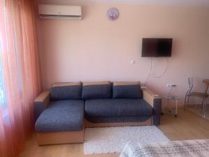a living room with a blue couch and a tv at Studio Fatinia in Byala