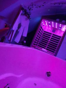 Heaven Loft في إيفتو: حوض استحمام وردي في غرفة مع أضواء أرجوانية