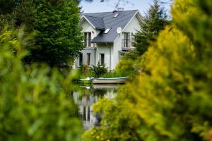 a house on the water with a boat in front at Leśny Dworek in Darłowo