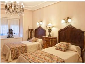 a bedroom with two beds and a chandelier at H. Boutique Puerta del Sol in Torrelavega