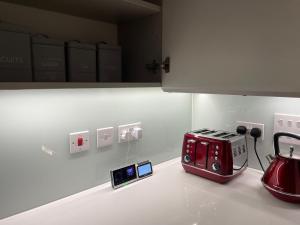 eine Küchentheke mit einem roten Toaster und zwei Uhren in der Unterkunft Modern & Spacious Penthouse in North London in London