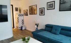 - un salon avec un canapé bleu et des photos sur le mur dans l'établissement Magnifique Vue mer pour ce T2 totalement rénové classé meublé de tourisme 3 etoiles, à Dunkerque