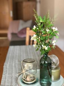 a green vase with white flowers on a table at Ferienhaus Mautzfried in Reisach