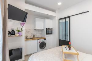 a white kitchen with a washing machine and a table at Tulipe : Studio proche RER B Cachan in Cachan