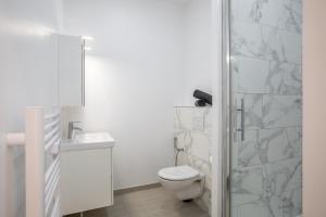 a white bathroom with a toilet and a shower at Tulipe : Studio proche RER B Cachan in Cachan