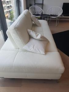 a white couch with pillows on it in a room at Nieuwbouwappartement Lippenslaan met 2 slaapkamers - WIFI - 6 personen in Knokke-Heist