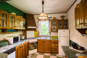 a kitchen with wooden cabinets and a white refrigerator at Leśny Dworek in Darłowo