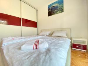 a white bed with red and white pillows on it at Guest House Ivano in Mostar