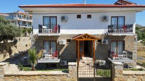 ein Steinhaus mit roten Stühlen auf dem Balkon in der Unterkunft Gökçeada Deep Breath in Canakkale