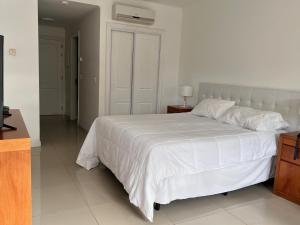 um quarto com uma grande cama branca e uma mesa de cabeceira em Monoambiente Green Park em Punta del Este