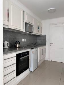a white kitchen with white cabinets and a black appliance at Monoambiente Green Park in Punta del Este