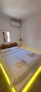 a bed room with a white bedspread and a lamp on the wall at Eternal Town in Mikonos