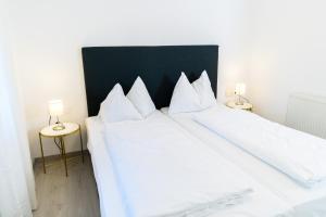 2 weiße Betten in einem Zimmer mit 2 Lampen in der Unterkunft Seeappartements Christiane Haus 95 in Leinsdorf
