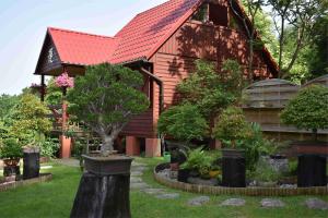 a red roofed house with trees in front of it at Ogród Shinrin Yoku Odpoczynek w Lesie in Srokowo