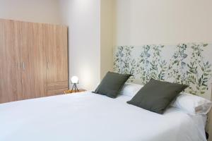 ein Schlafzimmer mit einem großen weißen Bett mit zwei Kissen in der Unterkunft AP TURIST VELÁZQUEZ in Alicante