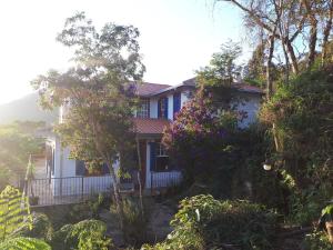 una casa con árboles y flores delante de ella en Solar dos Reis Apartamento Topázio en Ouro Preto