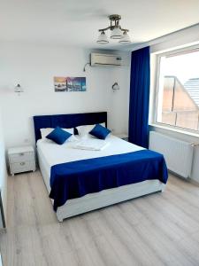 a bedroom with a bed with blue sheets and a window at Vila Coty in Mamaia Nord