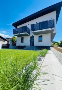 a white house with a green lawn in front of it at Apartmány TAMKA in Vrbov