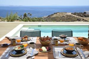 a table with food on it next to a swimming pool at KYNARA Boutique Village in Tinos Town