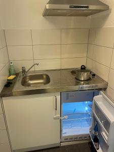 una pequeña cocina con fregadero y nevera abierta en City living 2 en Schwäbisch Hall