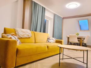 Raciąż的住宿－Apartament nad BRDĄ , agroturystyka.，客厅里一张黄色的沙发,配有桌子