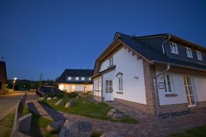 een klein wit huis met een zwart dak bij "GUTSHOFHÄUSER" Ferienhäuser Pendorf in Ostseebad Sellin