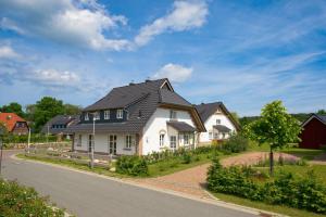 een wit huis met een zwart dak bij "GUTSHOFHÄUSER" Ferienhäuser Pendorf in Ostseebad Sellin