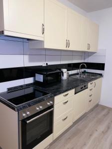 cocina con armarios blancos y encimera negra en Three bedroom apartment between Trogir and Split, en Kaštela