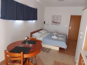 a small room with a table and a bed and a table and chairs at Apartments Burcul Pag in Pag