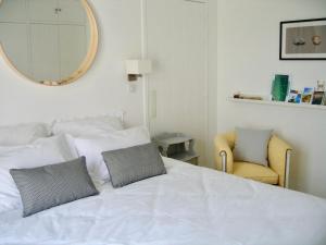 a bedroom with a white bed with a mirror and a chair at Le Clos des Fantaisies in Rivedoux-Plage