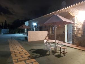 una mesa y sillas con una sombrilla en el patio por la noche en Los Duendes, en El Puerto de Santa María