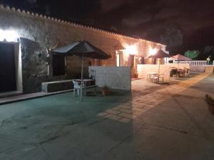 un patio con sombrilla, mesas y sillas por la noche en Los Duendes, en El Puerto de Santa María