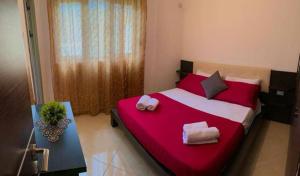 ein Schlafzimmer mit einem roten und weißen Bett mit Handtüchern darauf in der Unterkunft O-cyaneaalb in Vlorë