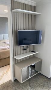 uma televisão de ecrã plano numa prateleira num quarto em APARTAMENTO PRAIA DE IRACEMA VISTA PARA o MAR 18 ANDAR em Fortaleza
