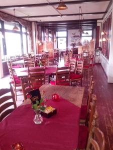 une salle à manger avec des tables, des chaises et un chiffon de table violet dans l'établissement Hotel Restaurant, à Anloo