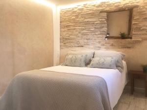 a bedroom with a white bed with a stone wall at Plaza Adarve Toledo in Toledo
